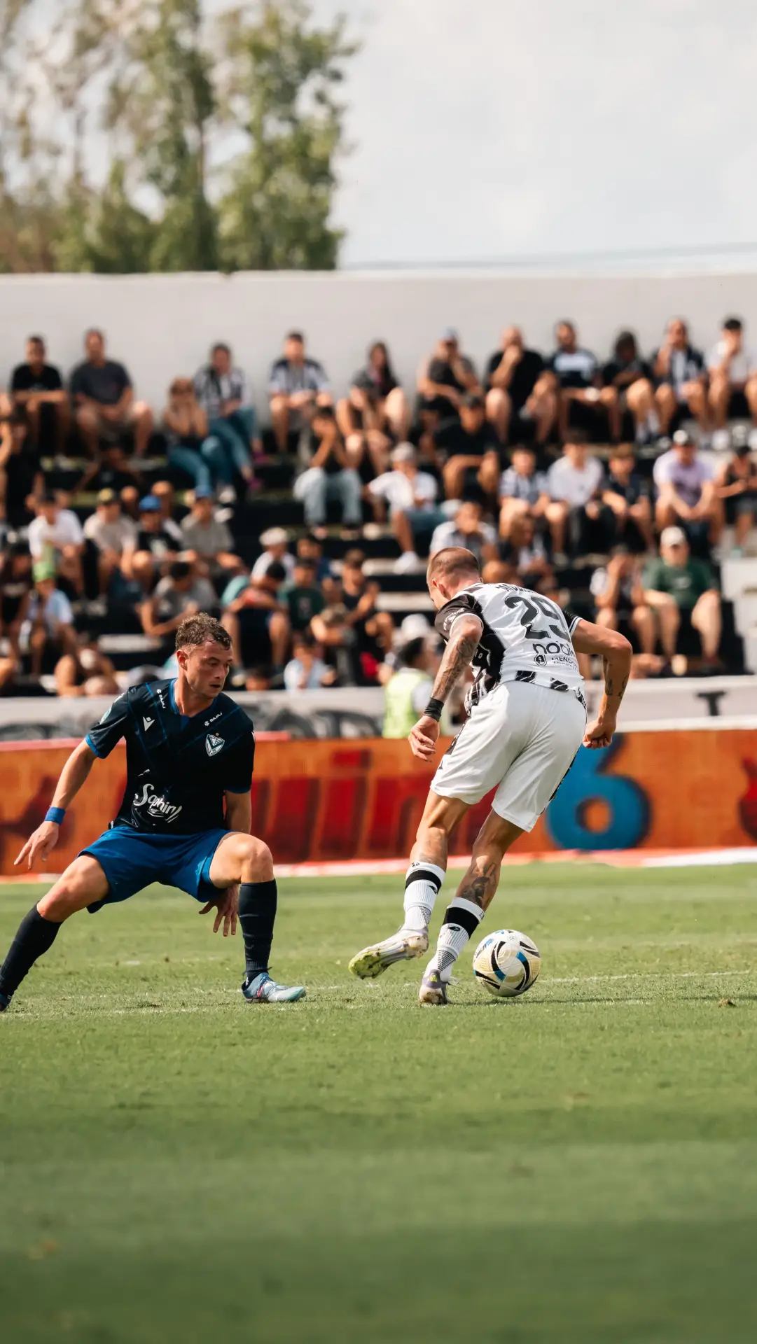 Two soccer players in action during a match with a crowd