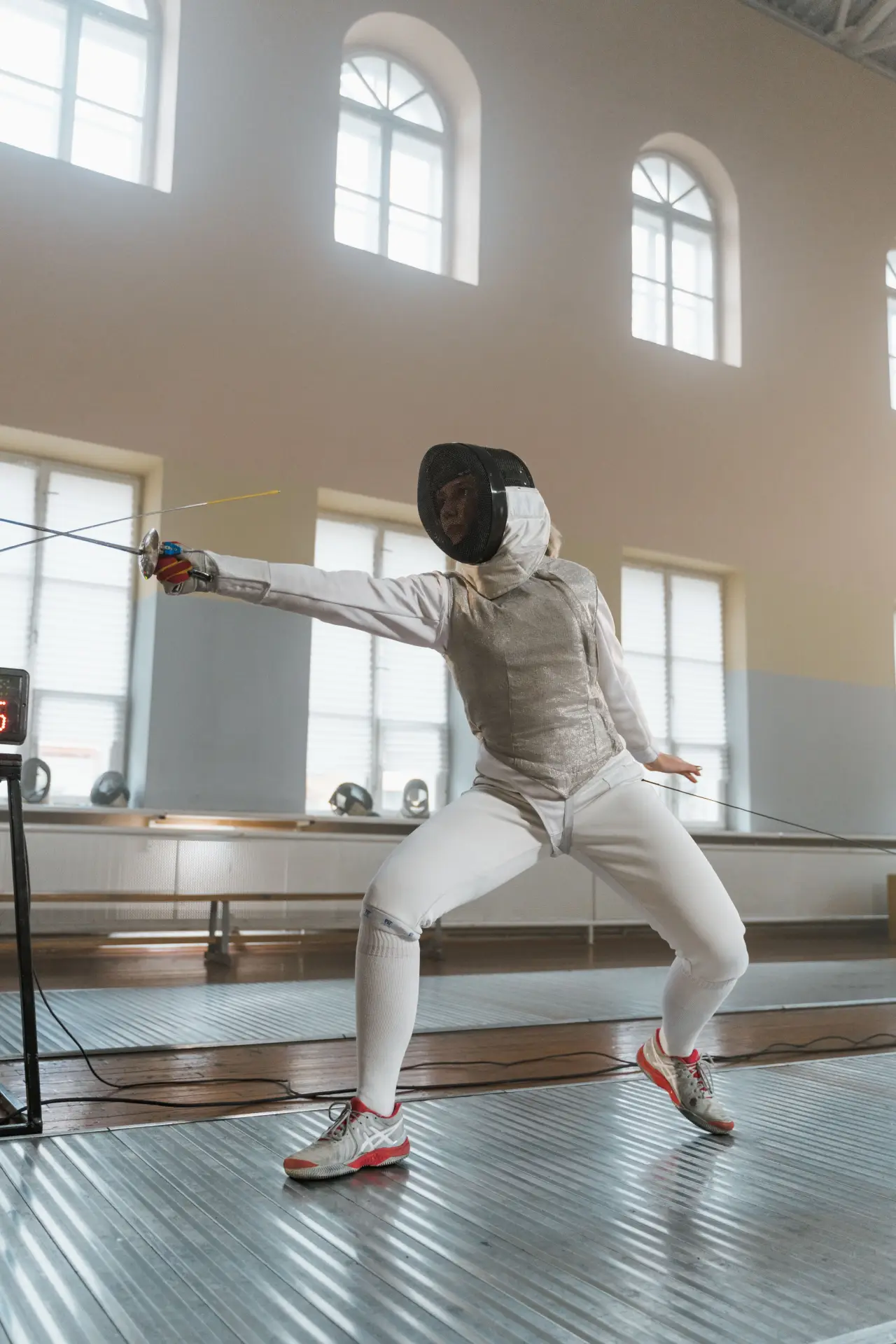 Fencer strikes a dynamic pose in an indoor fencing salle